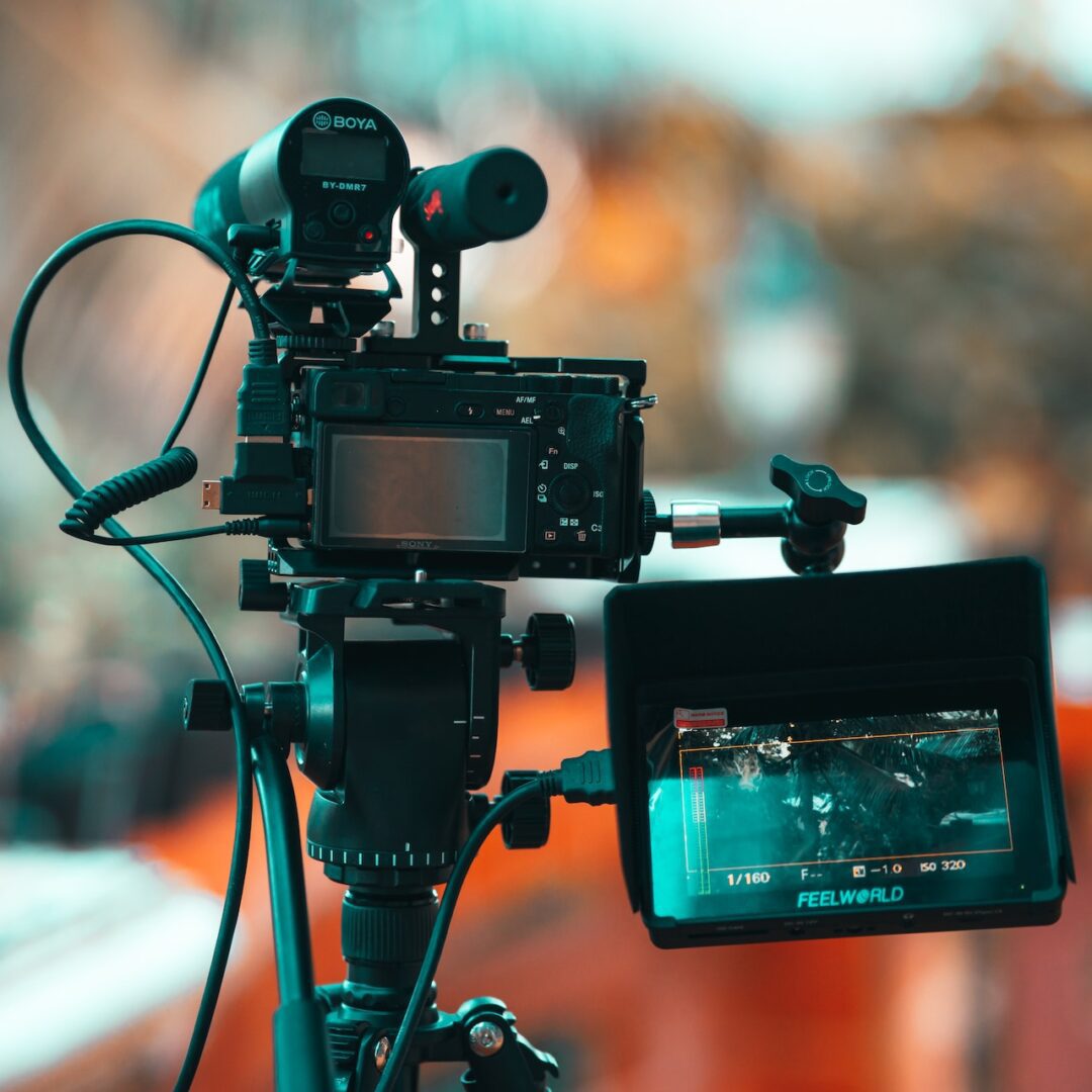 A camera on top of a tripod with a video monitor.