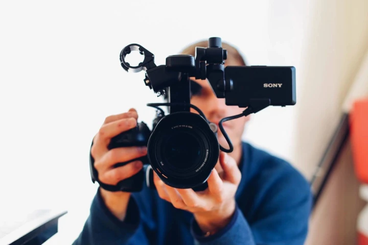 A man holding a camera up to the side of his face.